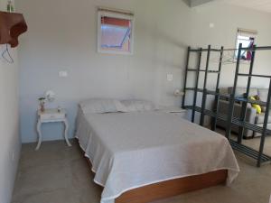 a white bedroom with a bed and a ladder at Vila Juma in Camburi