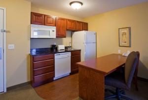 a kitchen with a table and a white refrigerator at GrandStay Residential Suites Hotel Faribault in Faribault