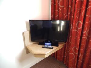 a flat screen tv sitting on top of a wooden table at Airport Inn Gatwick in Horley
