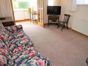 a living room with a couch and a television at Rowan Cottage in New Galloway