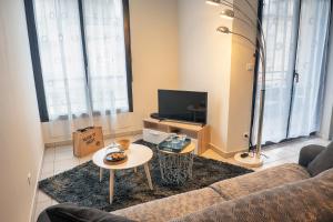 a living room with a couch and a tv at FIRMIN MARBEAU #13 - Espace citadin - 1 Chambre in Brive-la-Gaillarde