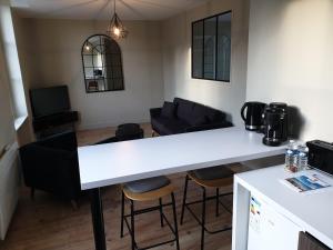 a kitchen and living room with a white counter and chairs at Au Loup Historic Apartments in Bayeux