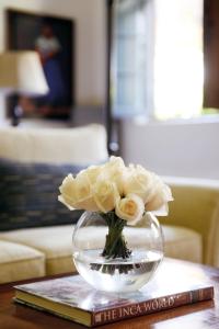 a vase filled with white roses sitting on top of a book at Palacio Nazarenas, A Belmond Hotel, Cusco in Cusco