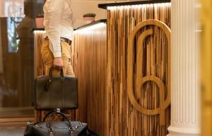 une personne debout à côté d'un panneau avec une valise dans l'établissement Hotel des Quinconces Bordeaux Centre, à Bordeaux