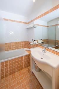 a bathroom with a sink, mirror, and tub at Colonna Grand Hotel Capo Testa in Santa Teresa Gallura