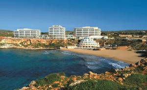 a view of a beach with buildings in the background at Radisson Blu Resort & Spa, Malta Golden Sands in Mellieħa