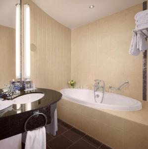 a bathroom with a tub, sink, and mirror at Radisson Blu Hotel Belfast in Belfast