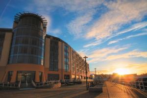 a building on a street in front of a sunset at Radisson Blu Waterfront Hotel, Jersey in Saint Helier Jersey