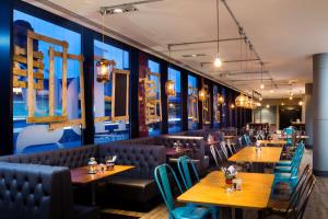a restaurant with wooden tables and blue chairs at Park Inn by Radisson Manchester City Centre in Manchester