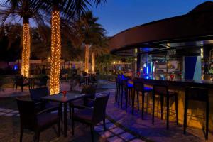 a restaurant with tables, chairs and umbrellas at Radisson Blu Hotel, Muscat in Muscat
