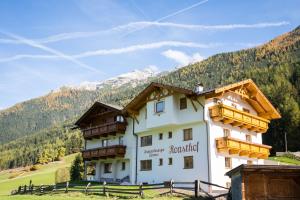 a large white building with a mountain in the background at Pension Roasthof in Neustift im Stubaital