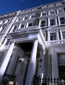 a white building with columns and a fence in front of it at Oxbridge Apartments in London