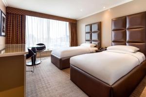 希灵登Radisson Blu Hotel, London Heathrow的有两张床和一张书桌的酒店房间