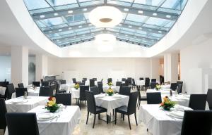 a dining room with white tables and black chairs at Hotel Lido in Alba Adriatica