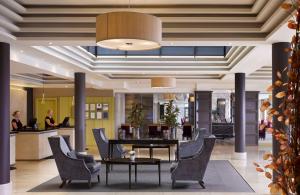 Radisson BLU Hotel & Spa, Sligo في سليغو: لوبي مكتب مع طاولة وكراسي وامرأة