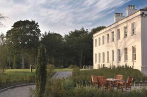 einen Tisch und Stühle vor einem weißen Gebäude in der Unterkunft Radisson BLU Hotel & Spa, Little Island Cork in Cork