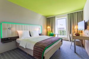 a hotel room with a large bed and a desk at Park Inn by Radisson Frankfurt Airport in Frankfurt