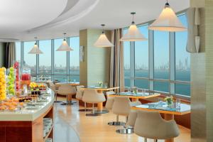 クウェートにあるSymphony Style Hotel Kuwaitのテーブルと椅子が備わるレストランで、水辺の景色を望めます。