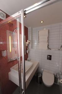 a bathroom with a toilet a sink and a shower at Park Inn by Radisson Poliarnie Zori in Murmansk
