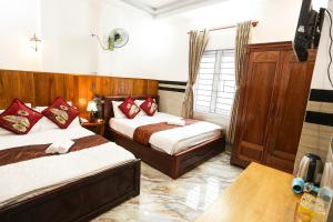 a bedroom with two beds and a tv in it at Lucky Hotel Quy Nhon in Quy Nhon