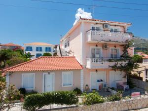 a large white house with a balcony on a hill at Theodora Studios & Apartments in Skala Kefalonias