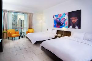 a hotel room with two beds and a large painting on the wall at Decapolis Hotel Panama City in Panama City