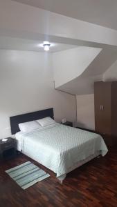 1 dormitorio con cama blanca y suelo de madera en BARRANQUITO SUITE, en Lima