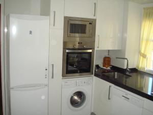 a kitchen with a washing machine and a microwave at Apartamentos Valles in Broto