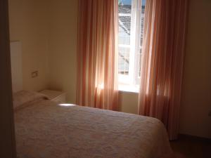 - une chambre avec un lit et une fenêtre avec des rideaux orange dans l'établissement Apartamentos Valles, à Broto