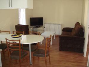 Una sala de estar con una mesa y sillas y un sofá. en Apartamentos Valles, en Broto