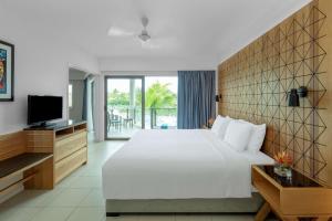 a bedroom with a large white bed and a television at Radisson Blu Resort Fiji in Denarau