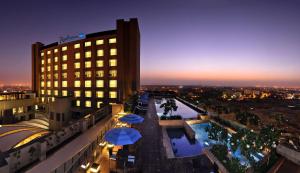 um hotel com guarda-sóis e uma piscina à noite em Radisson Blu Hotel New Delhi Paschim Vihar em Nova Deli