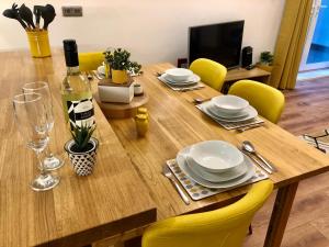a wooden table with yellow chairs and a bottle of wine at The Duplex with Air Conditioning & Private Deck Area in Margate
