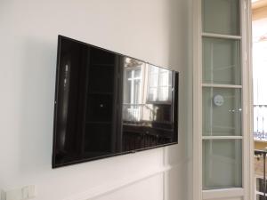 a flat screen tv on a wall next to two windows at Casita de Santos in Málaga +46 photos