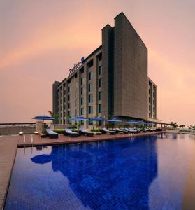 a hotel with a large swimming pool with chairs and umbrellas at Radisson Blu Hotel New Delhi Paschim Vihar in New Delhi