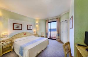 um quarto de hotel com uma cama grande e uma televisão em Grand Hotel Smeraldo Beach em Baja Sardinia