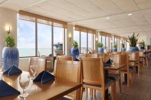 un restaurante con mesas y sillas de madera y el océano en DoubleTree by Hilton Corpus Christi Beachfront, en Corpus Christi