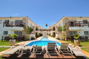 a resort with a swimming pool and chairs and buildings at Itamaracá Apartments in Itamaracá
