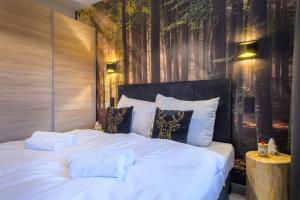 a bedroom with a large white bed with trees on the wall at Apartament Izerska Przygoda - 5D Apartamenty in Świeradów-Zdrój