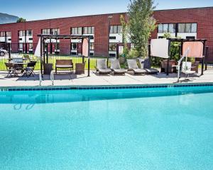 a swimming pool with chairs and a table and a building at The Cairn Hotel in Cedar City