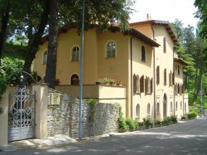 a yellow house with a gate and a stone wall at La Locanda del Borgo in Pietralunga