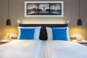 a bedroom with two beds with blue and white pillows at Radisson Blu Hotel, Mannheim in Mannheim