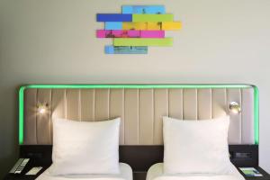 Park Inn by Radisson Izmir في إزمير: سرير مع وسادتين ولوحة على الحائط