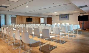 uma sala de conferências com cadeiras brancas e um ecrã em Radisson Blu Hotel Bordeaux em Bordeaux