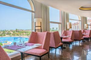 a restaurant with pink chairs and a pool at Radisson Blu Resort, Al Khobar Half Moon Bay in Half Moon Bay