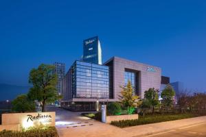 a large glass building with a tall skyscraper at Radisson Suzhou in Suzhou