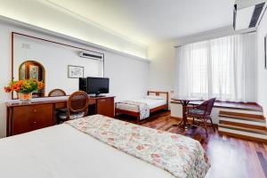 Cette chambre comprend deux lits, un bureau et une table. dans l'établissement Eurogarden Hotel, à Rome