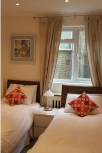 1 dormitorio con 2 camas y ventana en Oxbridge Apartments, en Londres