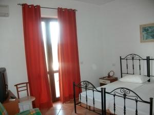 a bedroom with red curtains and a bed and a window at COUNTRY HOUSE SUL BUSSENTO in Torre Orsaia
