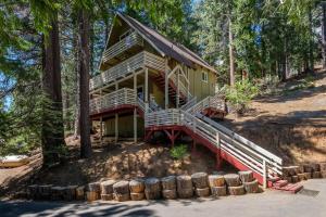 a log cabin in the woods with a large porch and stairs to it at Yosemite Hideaway A in Yosemite West